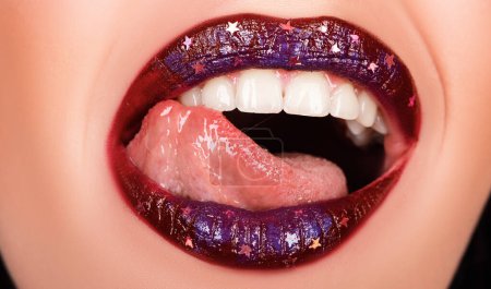 Foto de Mujer sexy maquillaje labios dientes aislados sobre fondo negro como arte pintado boca color metalizado con tono violeta. - Imagen libre de derechos