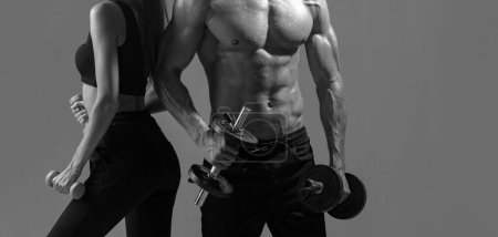 Photo for Sports people are working out with dumbbells. Fit couple doing exercise with dumbbells in dark studio. Muscular sexy couple body - Royalty Free Image