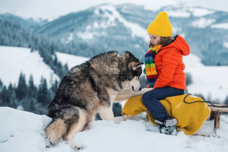 Foto de Perro Husky con niño en el paisaje invernal nevado. Invierno para niño. Tema Vacaciones de Navidad Año Nuevo - Imagen libre de derechos