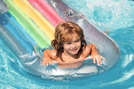 Téléchargez les photos : Vacances d'été. Enfant dans la piscine. L'été. Garçon souriant sur matelas gonflable en caoutchouc. - en image libre de droit