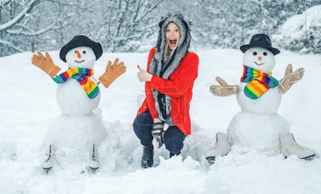 Foto de Funny Girl Love invierno. Chica feliz jugando con un muñeco de nieve en un paseo nevado de invierno - Imagen libre de derechos