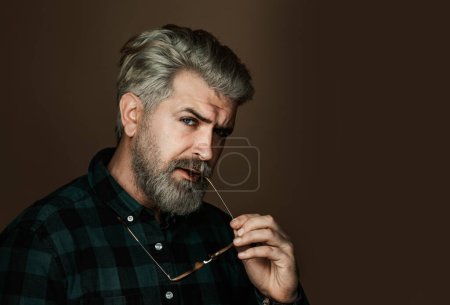 Foto de Hombre barbudo guapo posando sobre un fondo oscuro. Primer plano retrato del hombre de la moda mirando a la cámara - Imagen libre de derechos