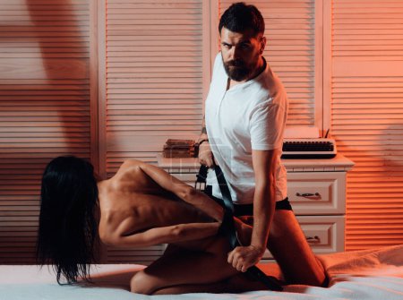 Bearded strong dominant man tied hands for his sexy hot girlfriend. Sexual abuse and rape. Home harassment woman. Sexy hot woman loving BDSM games