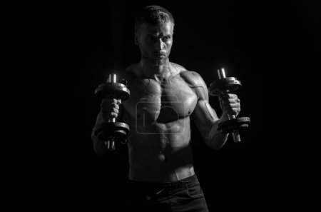 Photo for Portrait of young athlete doing exercise with dumbbell at isolated dark studio. Sexy sporty torso, man with dumbbells. Crossfit, sport and healthy lifestyle concept - Royalty Free Image