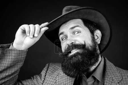 Photo for Handsome bearded polite man is happy to see someone. Men style and manners concept. Cheerful smiling gentleman takes off hat in salutation isolated at black background - Royalty Free Image