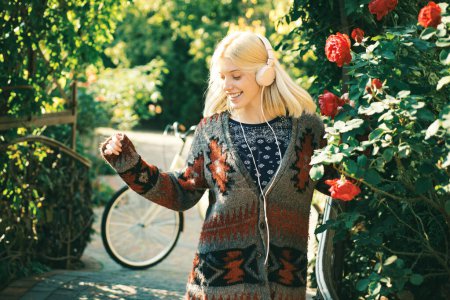 Photo for Close up portrait of a beautiful girl in warm sweater and headphones standing near colorful autumn leaves. Art work of romantic woman. Pretty tenderness model looking at camera - Royalty Free Image