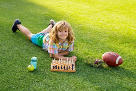 Téléchargez les photos : Clever concentrated and thinking kid boy playing chess - en image libre de droit