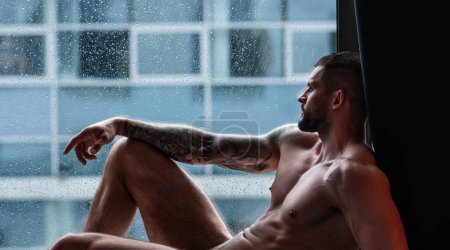 Foto de Muscular male torso, bare shoulders. Nude man in a bedroom. Young sexy body of strong man at morning. Muscular man in hotel room on window curtains. Shirtless topless sexy male model posing indoor - Imagen libre de derechos