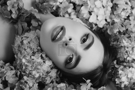 Foto de Belleza femenina. Chica acostada en flores. Unidad con la naturaleza. Blossom. Maquillaje cosméticos y cuidado de la piel - Imagen libre de derechos