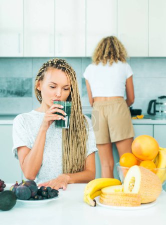 Photo for Woman with glass of natural detox smoothie in kitchen. organic food and vitamin. Vegetarian diet trend. Vegan concept. Ideal weight and weight loss. Making smoothie menu - Royalty Free Image
