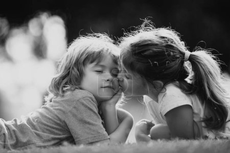 Téléchargez les photos : Charmant amour. Petite fille embrassant garçon à l'extérieur dans le parc. Relations enfants - en image libre de droit