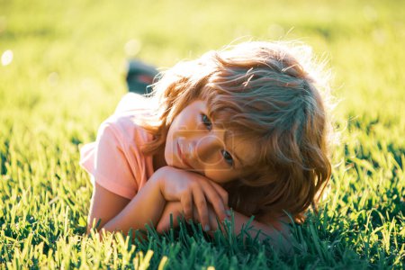 Photo for Children adaptation. Child in park outdoor. Spring kid lying on grass. Summer boy walk - Royalty Free Image