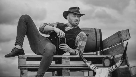 Photo for Sexy western man with cowboy hat. Attractive man with whiskey or brandy - Royalty Free Image