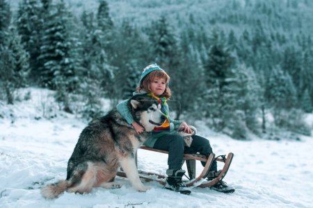 Foto de Niño de invierno. Niño divirtiéndose con perro husky en la nieve - Imagen libre de derechos