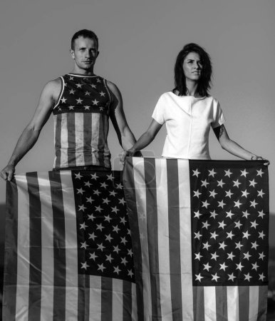 Téléchargez les photos : Couple amoureux célébrant la fête de l'indépendance au 4 juillet et tenant le drapeau américain. Le couple patriotique est fier de son pays. Étoiles et rayures drapeau américain - en image libre de droit