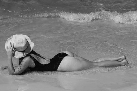 Photo for Summer vacation on beach. Woman in black swimwear lying on sandbeach. Girl enjoying sunbath near sea - Royalty Free Image