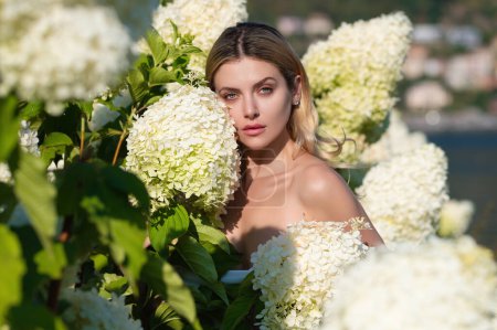 Foto de Joven mujer sexy o niña en flor arbusto de hortensias flores sobre fondo natural en el jardín. Grandes arbustos de hortensias blancas flores. Atractivo ramo de hortensias blancas - Imagen libre de derechos