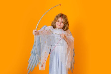 Photo for Kid cupid hold bow and arrow. Child angel. Portrait of cute kid with angel wings isolated on yellow studio background. Little angel, valentines day. Angelic kids - Royalty Free Image