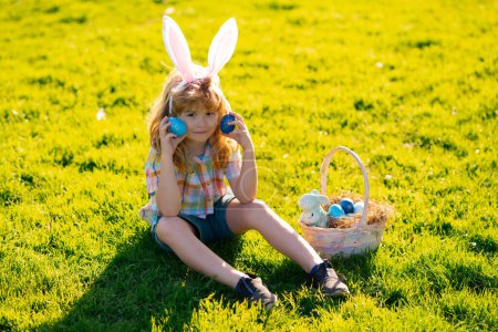 Photo for Kids boy in bunny ears hunting easter eggs outdoor. Child having easter in park. Easter egg hunt - Royalty Free Image