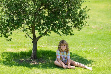Photo for Kid boy girl resting on green grass. Kids playing outdoors in summer park. Freedom and carefree. Happy childhood. Relaxing kid in green field during summer - Royalty Free Image