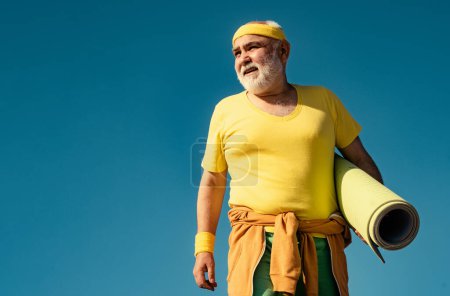 Photo for Senior man is doing fitness training. Funny sporty old sportsman finished his work out. Cheerful aged men holding yoga mats. Be in motion - Royalty Free Image