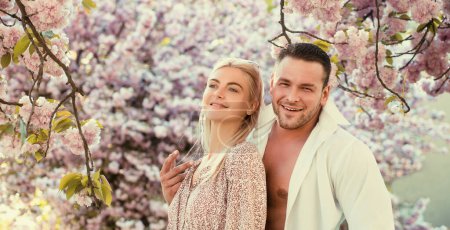 Foto de Los amantes tienen momentos románticos. Sensual pareja mujer y hombre en flores de color rosa en el parque de flores de verano - Imagen libre de derechos