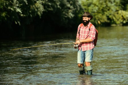 Foto de Hombre de pesca y relajarse mientras disfruta de hobby. Un pescador con caña de pescar en el río. Pescador y trucha. Manteniendo trucha marrón - Imagen libre de derechos