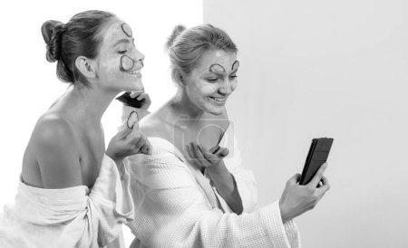 Téléchargez les photos : Les jeunes femmes naturelles sourient et font des procédures de spa pour la santé de leur peau. Les filles prennent selfie et s'amusent. Concept santé et beauté - en image libre de droit