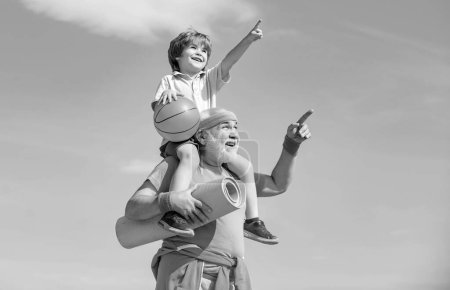 Téléchargez les photos : Heureux grand-père donnant petit-fils balade sur ses épaules pointant et levant les yeux. Différentes générations - en image libre de droit