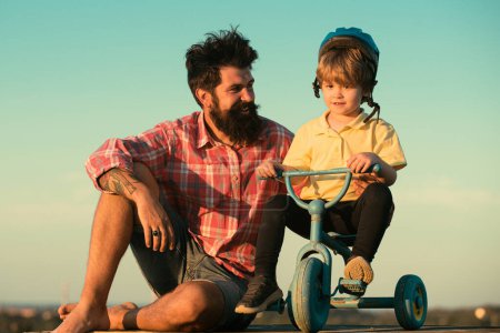 Foto de Familia cariñosa Padre e hijo. Papá ayuda a su hijo a montar en bicicleta - Imagen libre de derechos
