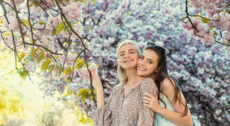 Foto de Dos mujeres jóvenes relajándose en flores de sakura. Chicas de primavera - Imagen libre de derechos