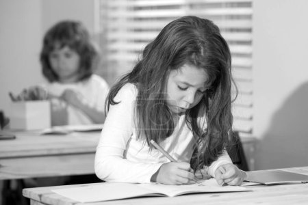 Photo for Portrait of cute girl sitting at desk in school classroom. Pupil drawing, preschool child study at school. Children education, homeschooling concept - Royalty Free Image