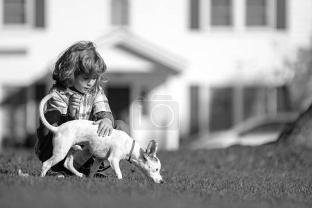 Foto de Dueña de un niño acariciando suavemente a su perro. Niño feliz y cachorro la abraza con ternura - Imagen libre de derechos