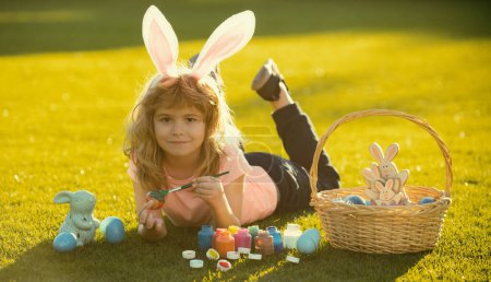Photo for Children celebrating easter painting eggs. Kid in rabbit costume with bunny ears outdoor - Royalty Free Image