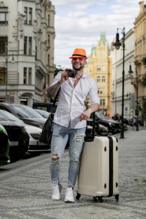 Foto de Estudiante viajero o joven turista. Hombre viajero con maleta al aire libre. Turista hombre teniendo viaje de vacaciones - Imagen libre de derechos