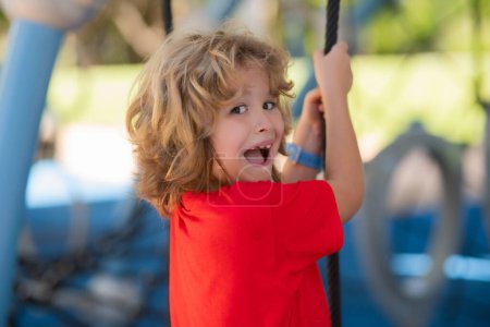 Foto de Little excited boy playing on the playground. The emotion of happiness, fun, joy. Smile of a child - Imagen libre de derechos