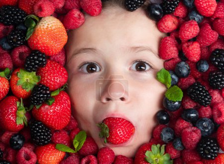 Téléchargez les photos : Top view photo of child face with berri. Berry set near kids face. Cute little boy eats strawberries. Kid eating vitamins. Close up kids face. Funny kids face close up - en image libre de droit