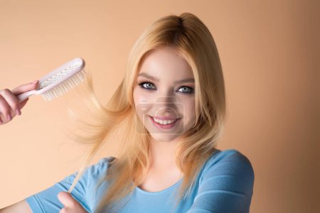 Foto de Beautiful woman with brush combing hair. Beauty girl with straight hair isolated on studio background. Woman hold hairbrush near face. Healthy hair. Hairstyle and hair care concept. Shiny hairs - Imagen libre de derechos