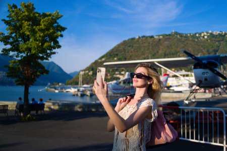Téléchargez les photos : Beautiful model walks away from her private jet on holiday. Business woman near private jet. Luxury travel in Como lake Italy. Charter jet airplane. Sensual woman on the street near jet plane - en image libre de droit
