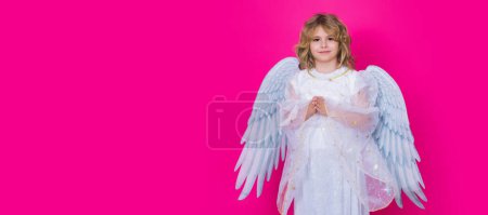 Foto de Cute angel kid, studio portrait. Banner header, copy space. Blonde curly little angel child with angels wings with prayer hands, hope and pray concept, isolated background - Imagen libre de derechos