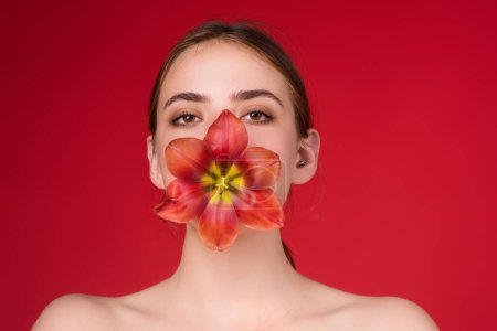 Photo for Beauty girl with tulip in mouth. Beautiful sensual woman hold tulips, studio portrait on red background - Royalty Free Image