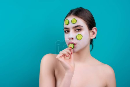 Téléchargez les photos : Woman apply facial mask isolated over blue studio background. Spa, cosmetic mask. Beautiful woman with clay facial mask. Skin care, peeling, moisturising and beauty treatment concept - en image libre de droit