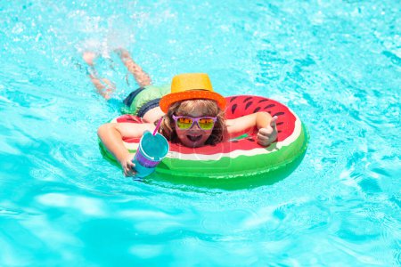 Téléchargez les photos : Happy kid playing with colorful swim ring in swimming pool on summer day. Child water vacation. Children play in tropical resort. Summer kids vacation, boy swim in pool - en image libre de droit