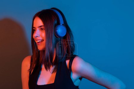 Photo for Happy young woman relaxed with great songin headphones, listens music, isolated over color neon background at studio - Royalty Free Image