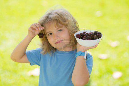 Photo for Summer child face. Kid picking and eating ripe cherries. Happy child holding fresh fruits. Healthy organic berry cherry fruit, summer season - Royalty Free Image
