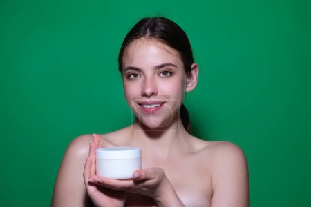 Téléchargez les photos : Beautiful woman applying moisturizer cream her face. Beauty concept. Skincare and pampering. Anti aging cream. Young model applyed cream. Girl applying cosmetic cream treatment on face - en image libre de droit