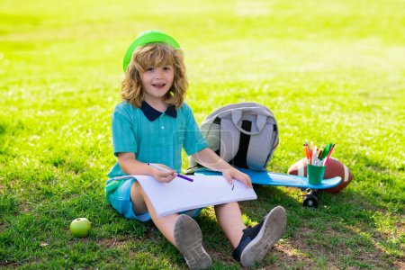 Téléchargez les photos : Des écoliers dessinent dans un parc d'été, peignent de l'art. Petit peintre dessiner des images en plein air - en image libre de droit