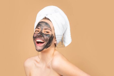 Téléchargez les photos : Facial black mud mask. Beautiful woman with charcoal facial mask on face. Cosmetic black clay masks. Portrait of beautiful spa girl. Beauty, healthcare - en image libre de droit