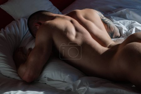 Photo for Young sexy man lying on a bed. Handsome young man with naked body, bare torso, undressed. Muscular young man laying on bed with naked muscular body. Sexy young male model - Royalty Free Image