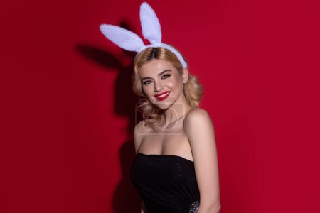 Photo for Portrait of a cheerful pretty young girl celebrating easter isolated over studio background. Studio photo of a young woman wearing bunny ears. Festive bunny - Royalty Free Image